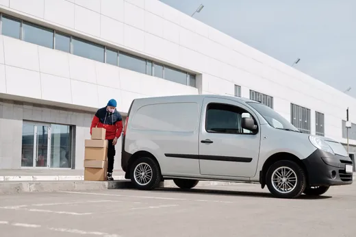 Camionnette de déménagement stationnée devant un bâtiment, prête au chargement