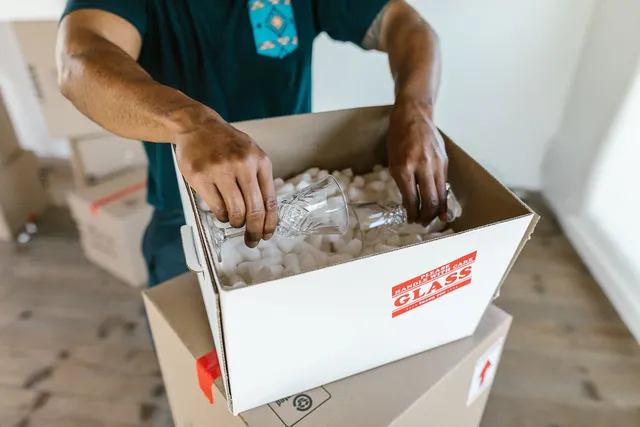 Déménageur emballant des verres avec du papier de protection dans un carton