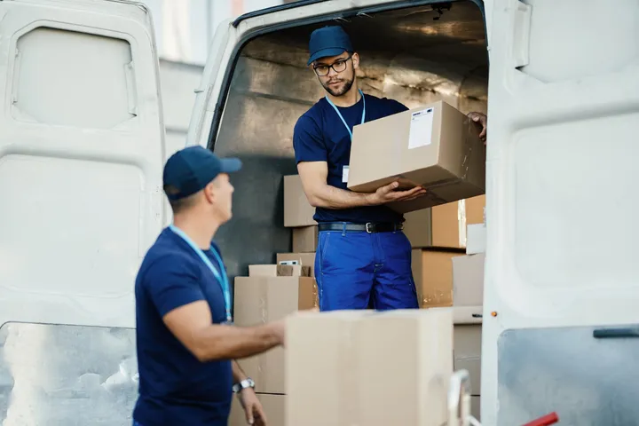 Équipe de déménageurs professionnels en uniforme chargeant des cartons dans le camion de déménagement